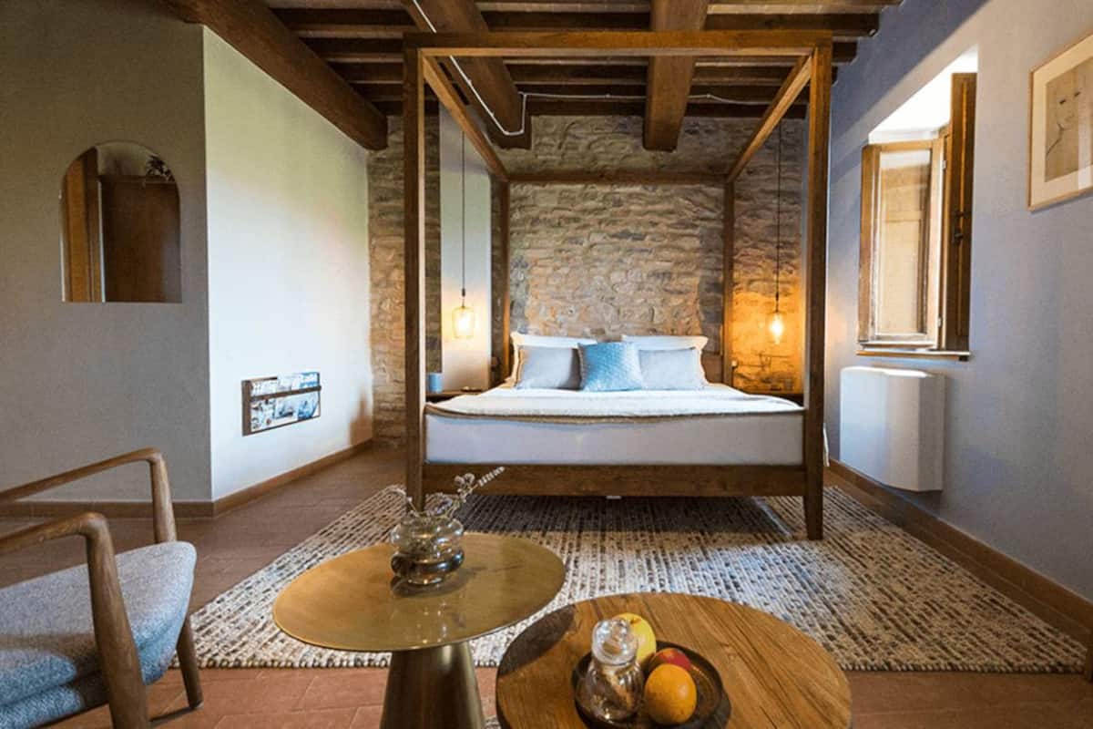 Un dormitorio acogedor con pared de piedra, estructura de cama de madera y una mesita con fruta.
