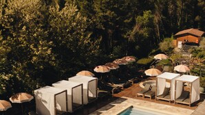 A pool area with lounge chairs and umbrellas, surrounded by lush greenery and hills. - Borgo Castello Panicaglia (Nocera Umbra)