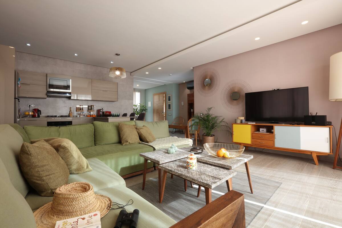 A modern living room with a green sofa, a coffee table, and a TV.