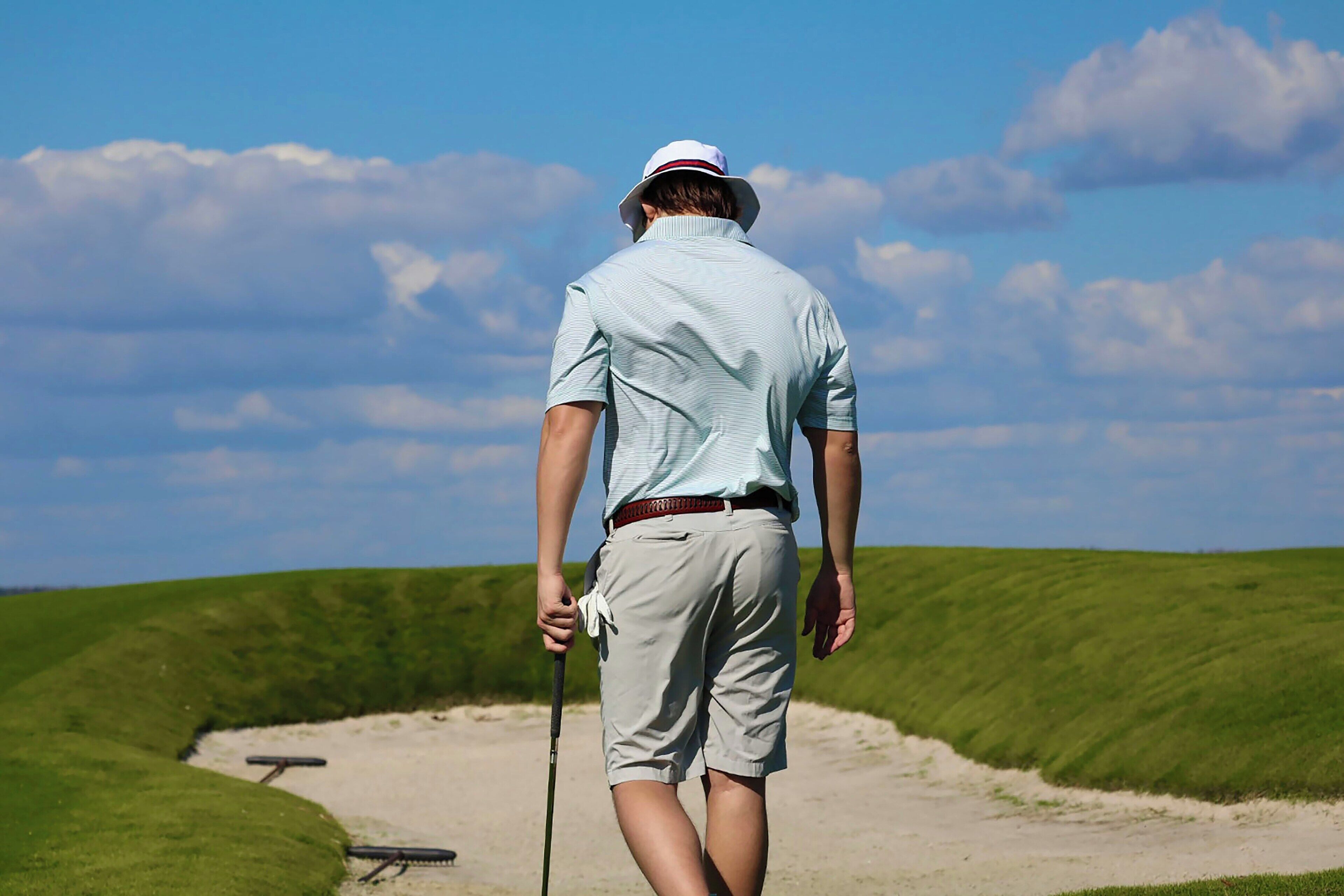 A person walking on a golf course with a golf club.