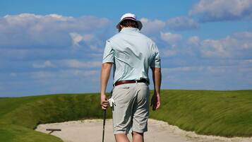 A person walking on a golf course with a golf club.