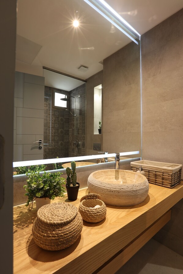 A modern bathroom with a large mirror, a round sink, and decorative woven baskets on the vanity. - YMY BEACH HOUSE (Tamri)