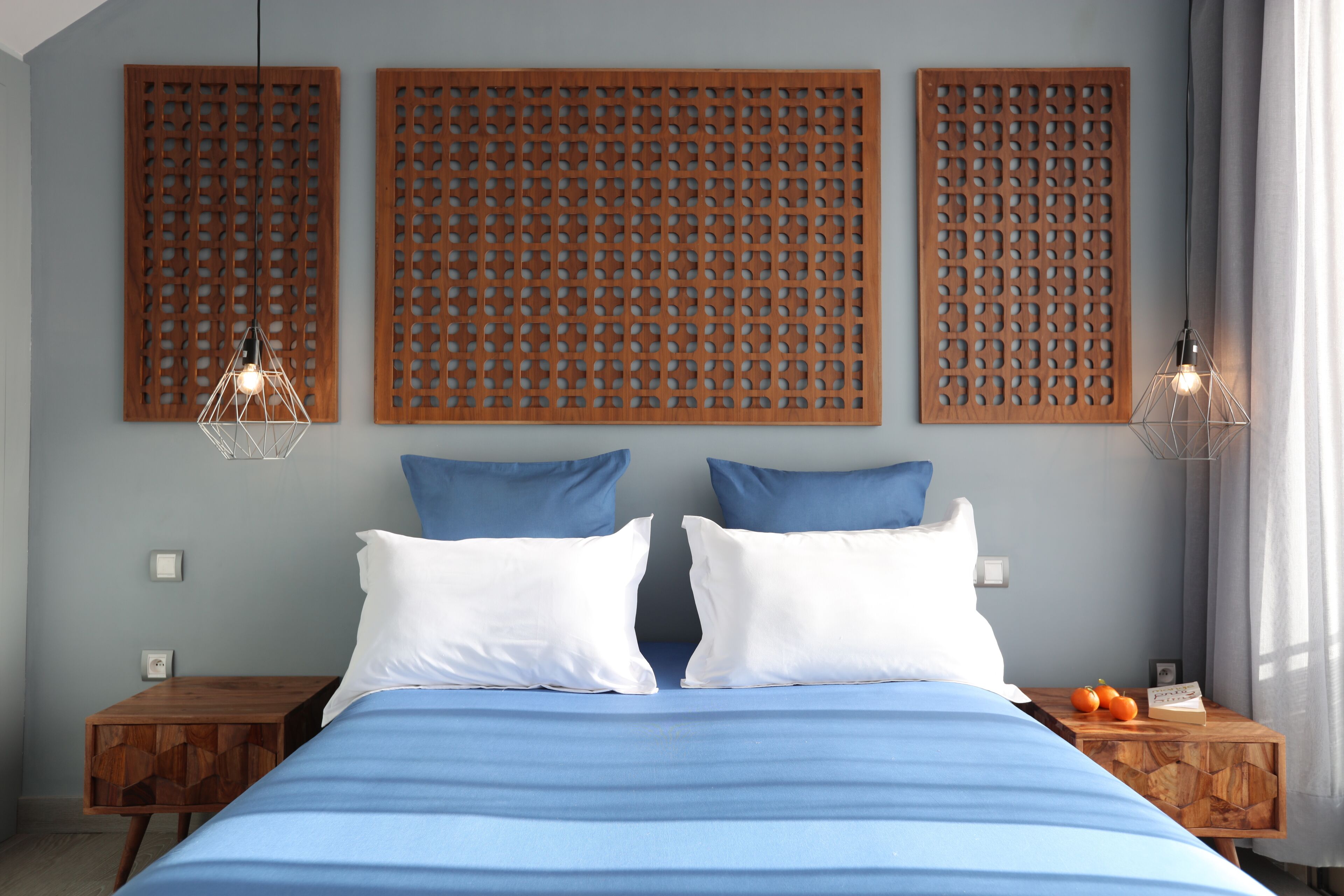 A bedroom with a bed, two nightstands, a wooden headboard, and a hanging light fixture.