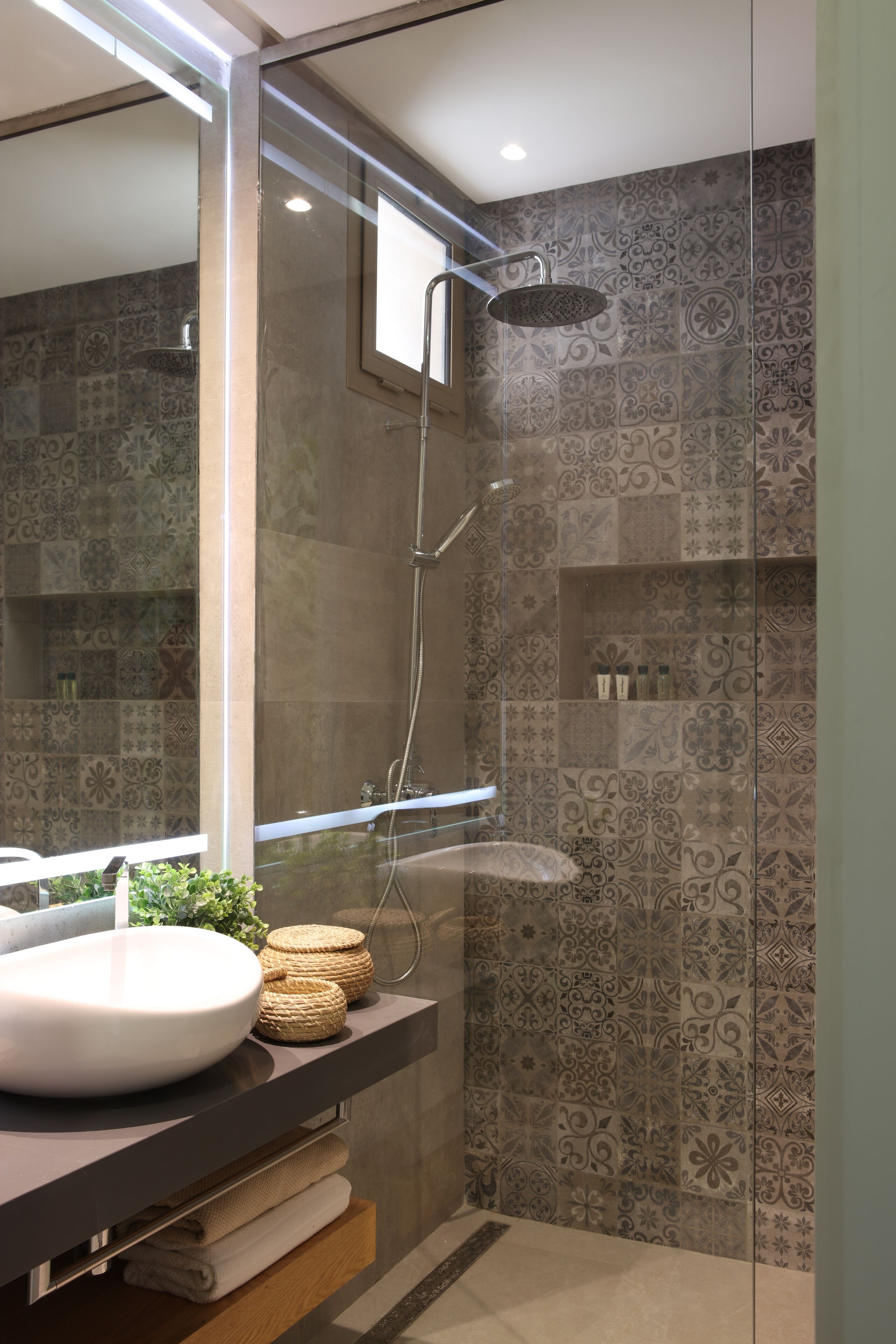 A modern bathroom with a large mirror, a round sink, and a shower with a glass enclosure.