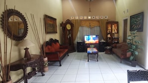 A living room with a sofa, armchairs, a coffee table, a TV, and decorative items.