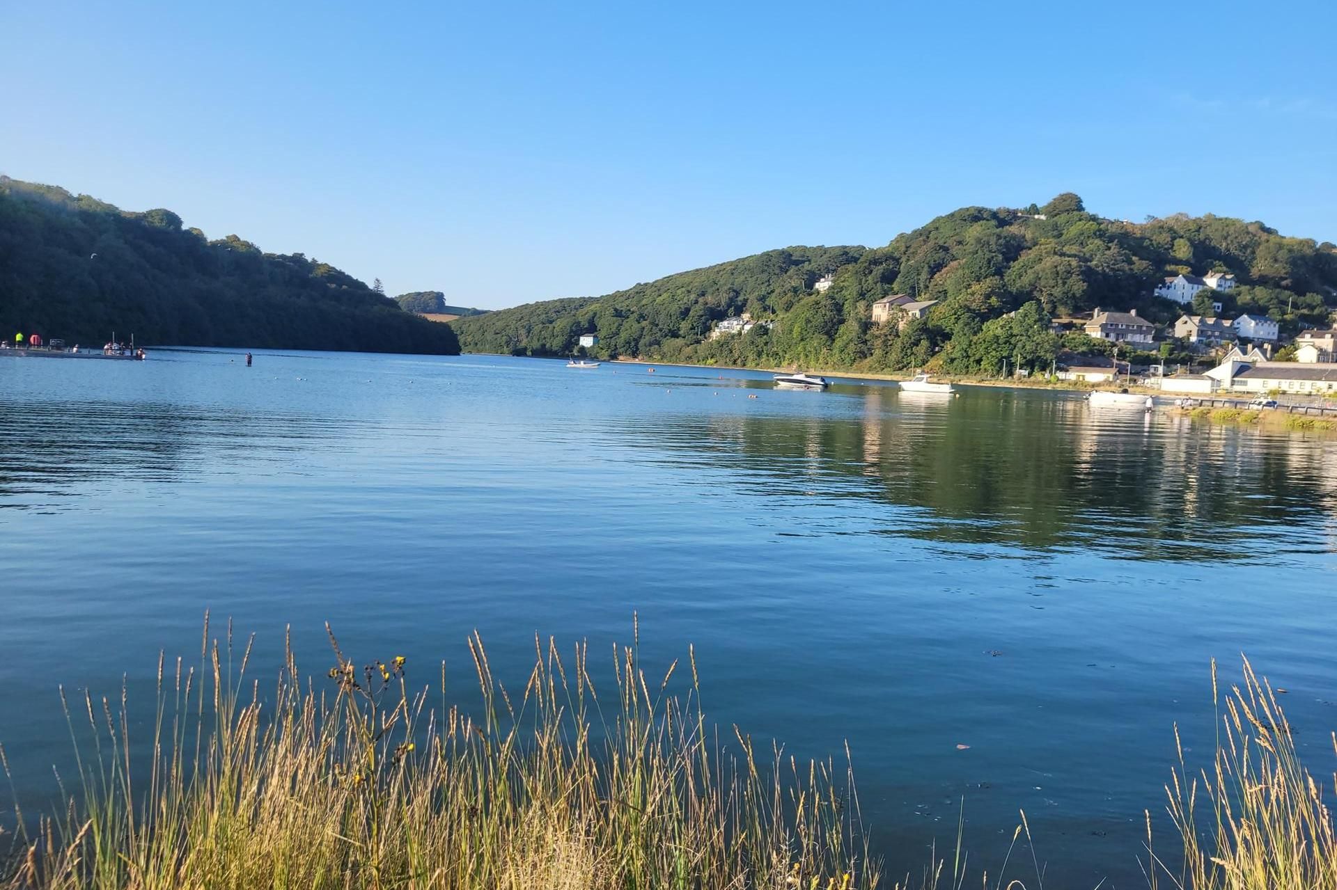 A calm lake with boats, surrounded by hills and residential buildings.