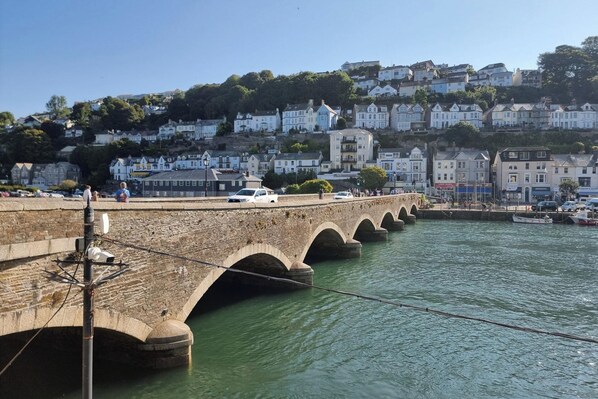 A stone bridge over a body of water with a town in the background. - Looe Cottage - Seaside Views, log Fire, Sleeps 4 (Looe)