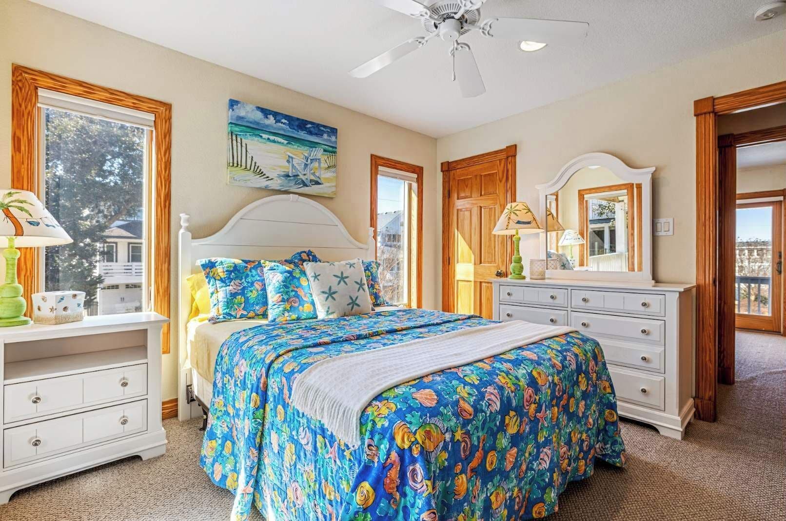 Une chambre à coucher comprenant un lit, une commode, une table de chevet et un ventilateur de plafond.