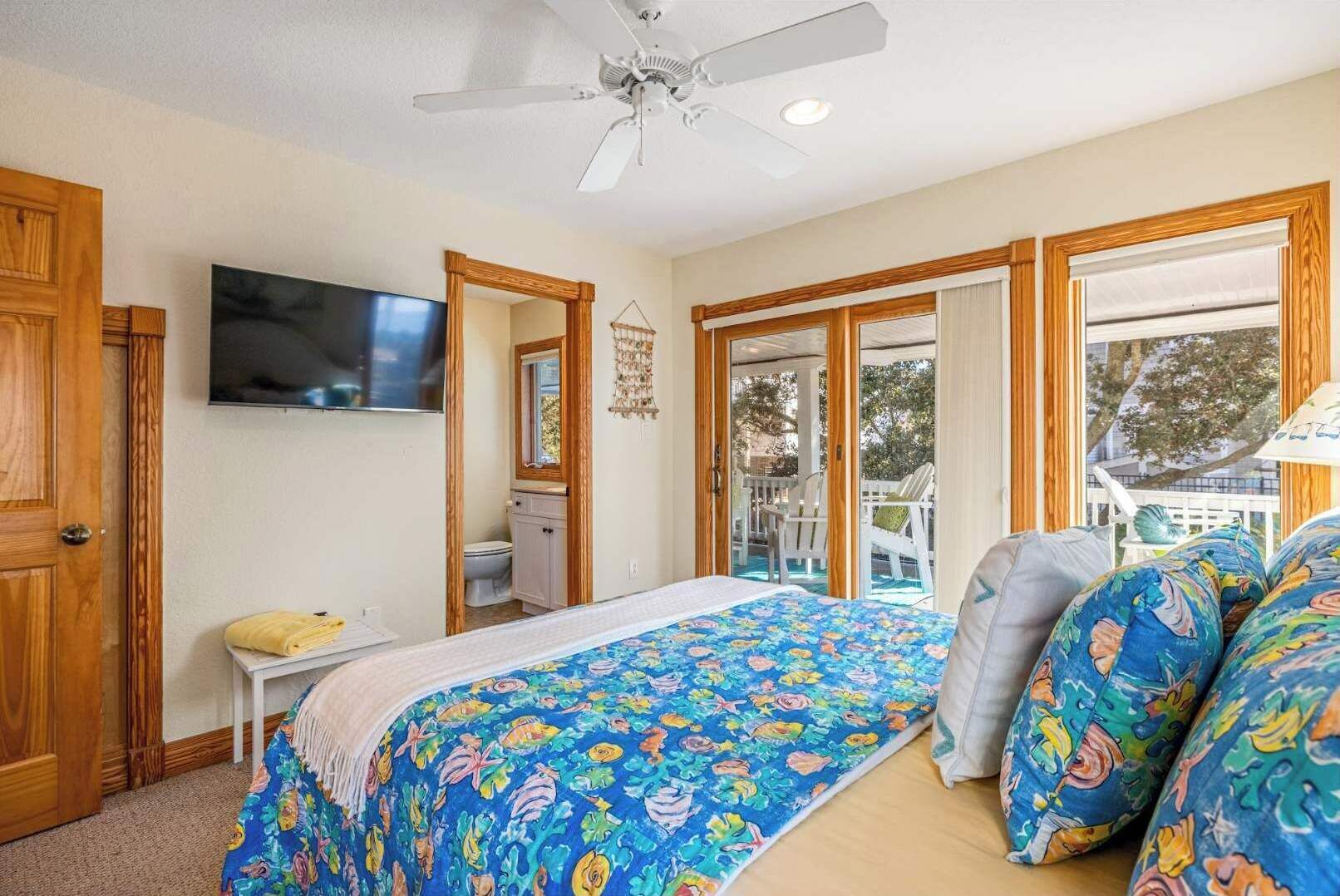 Ein Schlafzimmer mit Bett, Fernseher, Bad und einem Balkon mit Gartenmöbeln.