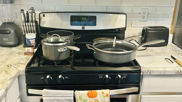 A kitchen with a stove, pots, a toaster, and a blender.