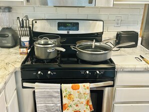 A kitchen with a stove, pots, a toaster, and a blender.