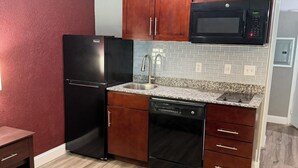 A compact kitchen with a refrigerator, microwave, sink, and dishwasher. - Fieldstone Apartments & Studios  (Fairmont)