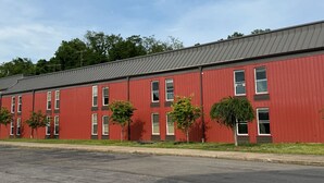 A red building with multiple windows and a flat roof. - Fieldstone Apartments & Studios  (Fairmont)