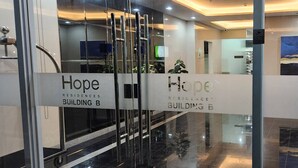A modern building entrance with glass doors and signs for 'Hope Residences Building B'. - Colin's Suite at Hope Residences (Trece Martires)