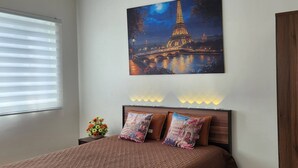 A bedroom with a bed, a night sky painting of the Eiffel Tower, a night light, and a wooden wardrobe. - Colin's Suite at Hope Residences (Trece Martires)