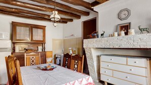 Una cocina con armarios de madera, una mesa de comedor con mantel a cuadros y un aparador blanco con cajones.