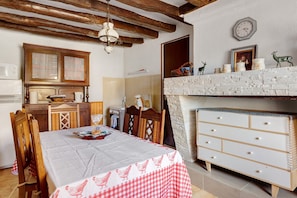 A kitchen with wooden cabinets, a dining table with a checkered tablecloth, and a white dresser with drawers. - Holiday Home 'Gîte 36 - 5 Km Zoo De Beauval' (Noyers-sur-Cher)