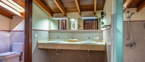A bathroom with two sinks, a toilet, and a shower.