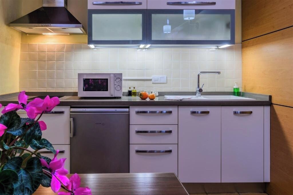 A modern kitchen with white cabinets, a microwave, and a sink.