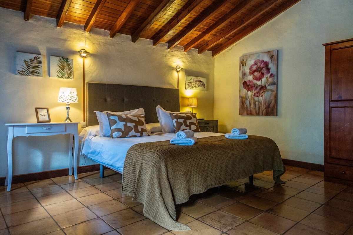 A bedroom with a bed, bedside lamps, a desk, and a wardrobe.