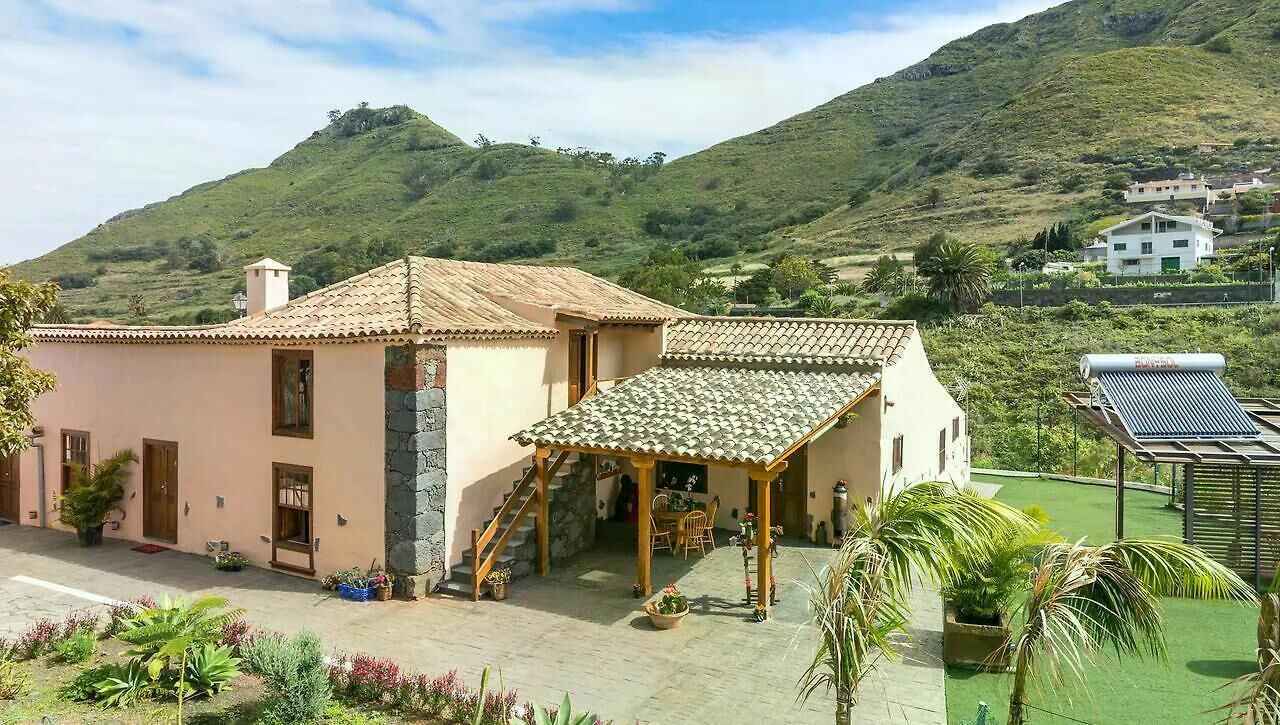 A two-story building with a tiled roof, a covered patio, and a garden area with potted plants.
