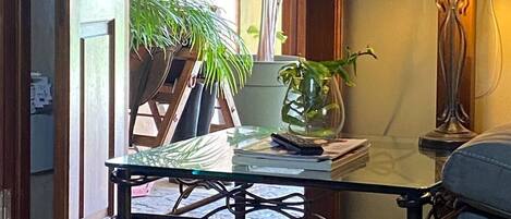 Une pièce avec une table en verre, une lampe et une plante en pot.
