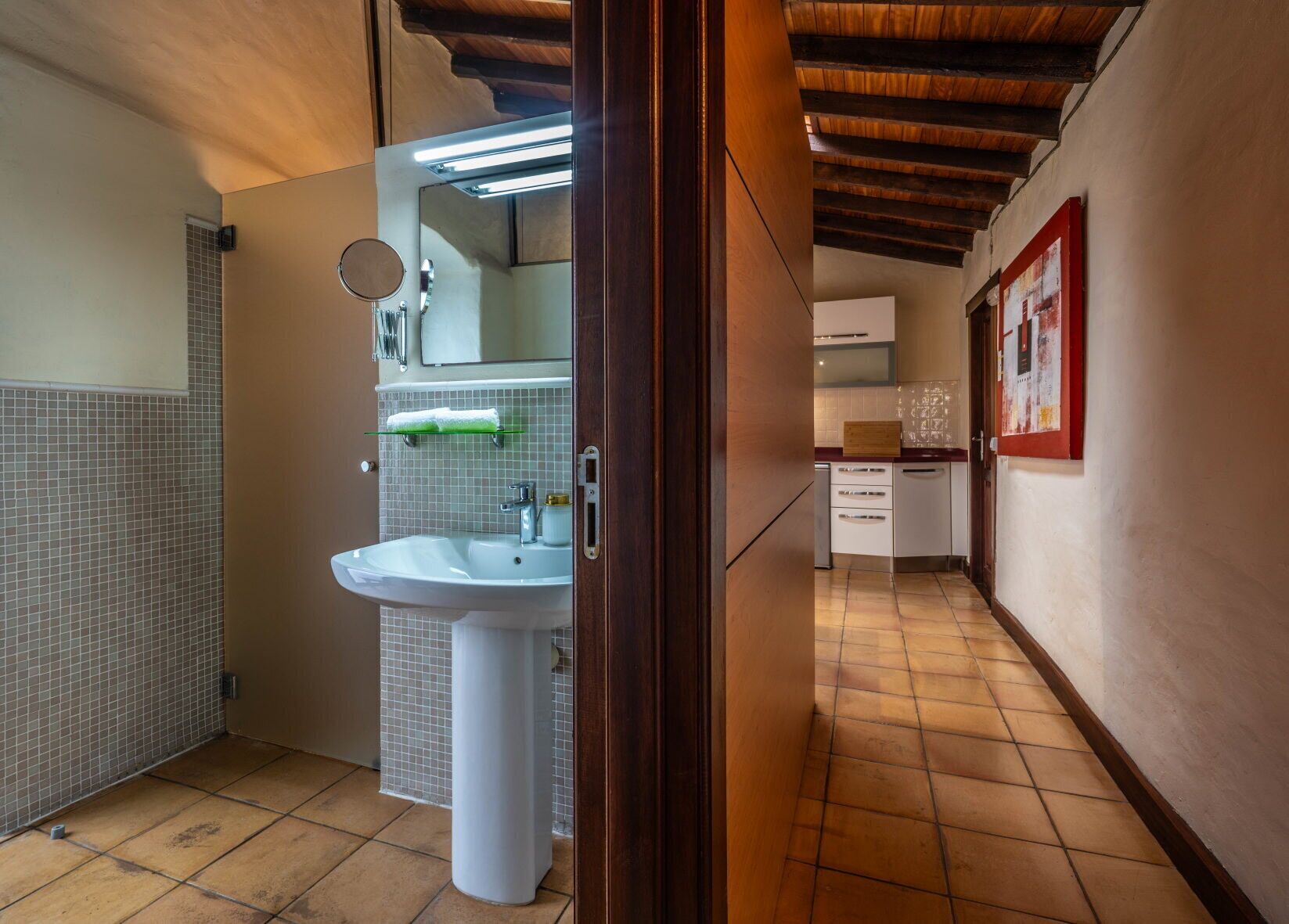 A bathroom with a white sink, mirror, and tiled walls.