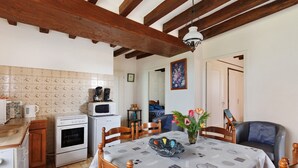A kitchen with a dining table, chairs, a microwave, an oven, and a wooden ceiling. - Holiday Home 'Gîte 264, Proche Zoo Beauval' with Private Terrace and Private Garden (Noyers-sur-Cher)