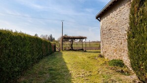 A stone building with a thatched structure in the background. - Holiday Home 'Gîte 264, Proche Zoo Beauval' with Private Terrace and Private Garden (Noyers-sur-Cher)