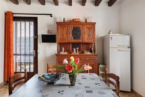 A dining area with a table, chairs, a vase with flowers, a wooden cabinet, and a refrigerator. - Holiday Home 'Gîte 264, Proche Zoo Beauval' with Private Terrace and Private Garden (Noyers-sur-Cher)
