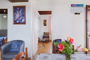 A room with a bed, a chair, a table with a vase of flowers, a calendar, and a painting on the wall. - Holiday Home 'Gîte 264, Proche Zoo Beauval' with Private Terrace and Private Garden (Noyers-sur-Cher)