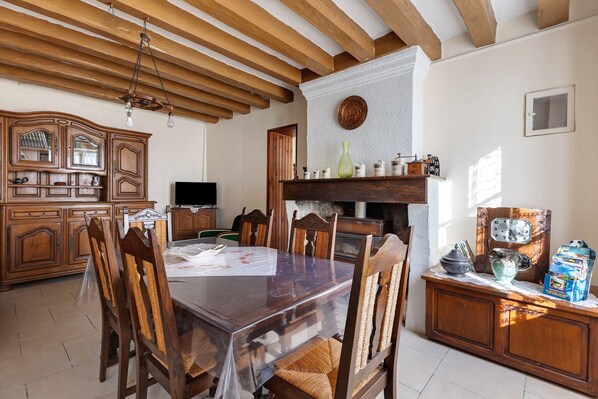 A dining area with a wooden table, chairs, a television, and a fireplace.