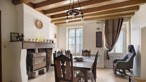 Ein Essbereich mit Holztisch, Stühlen, Kamin und Deckenbalken.