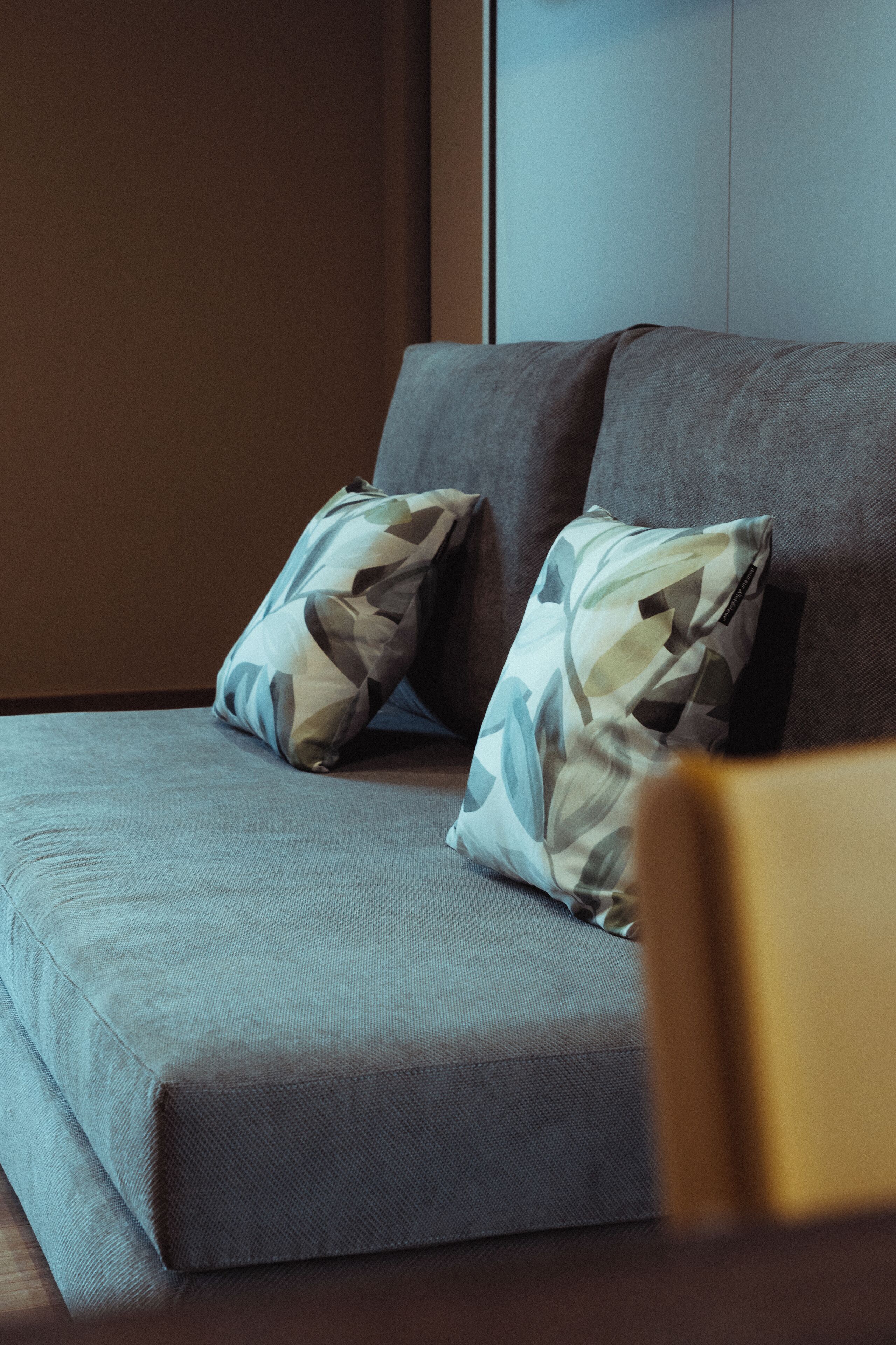 A modern living room with a grey sofa and patterned cushions.