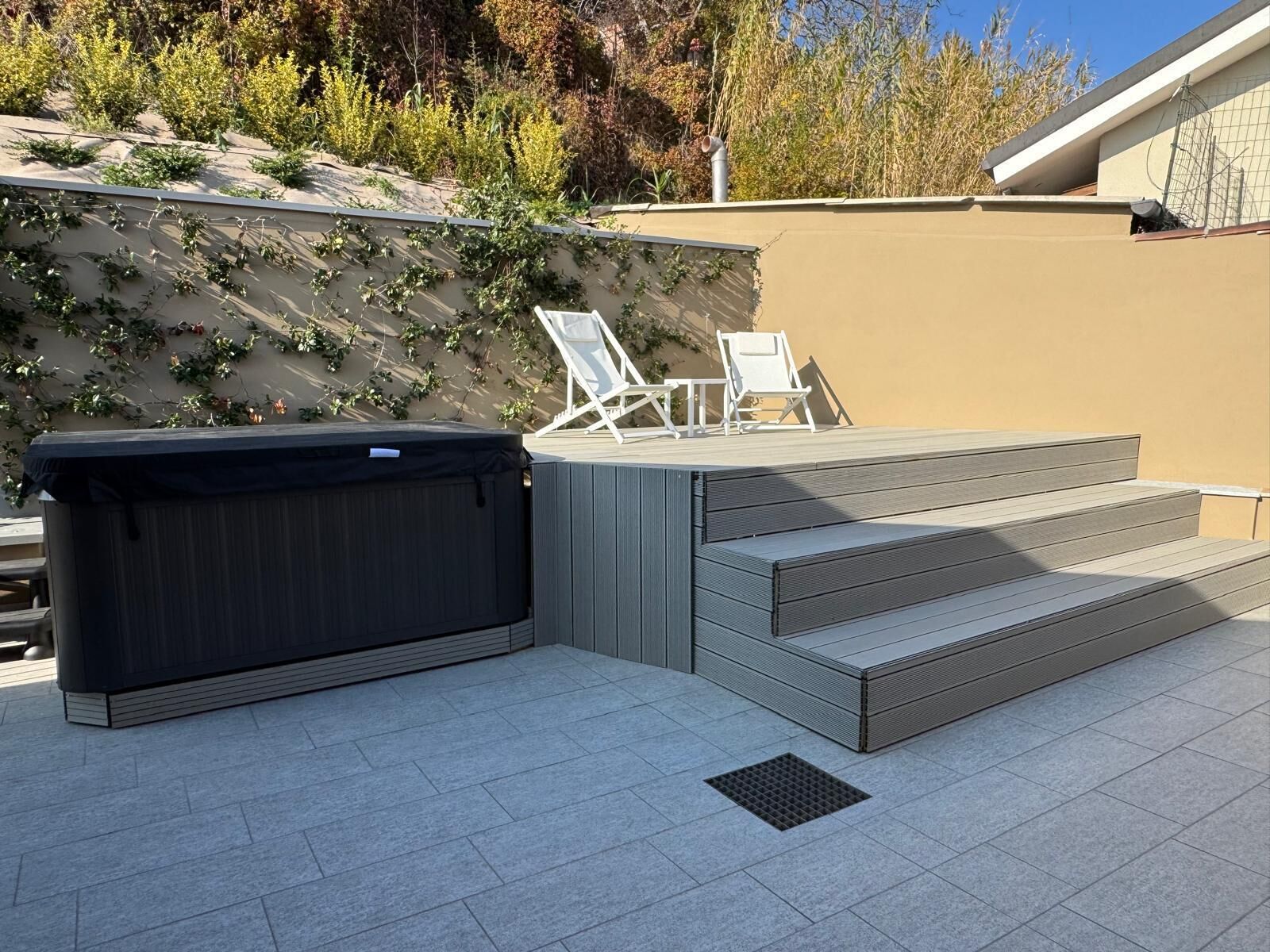 Eine Terrasse im Freien mit Whirlpool, Treppe und zwei Liegestühlen.