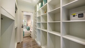 A hallway with a white wardrobe, a bed with a green pillow, and a safe. - Casa dos Quatro in Faro (Faro)