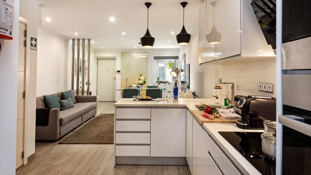 A modern kitchen with a central island, pendant lighting, and a dining area with a sofa and table. - Casa dos Quatro in Faro (Faro)