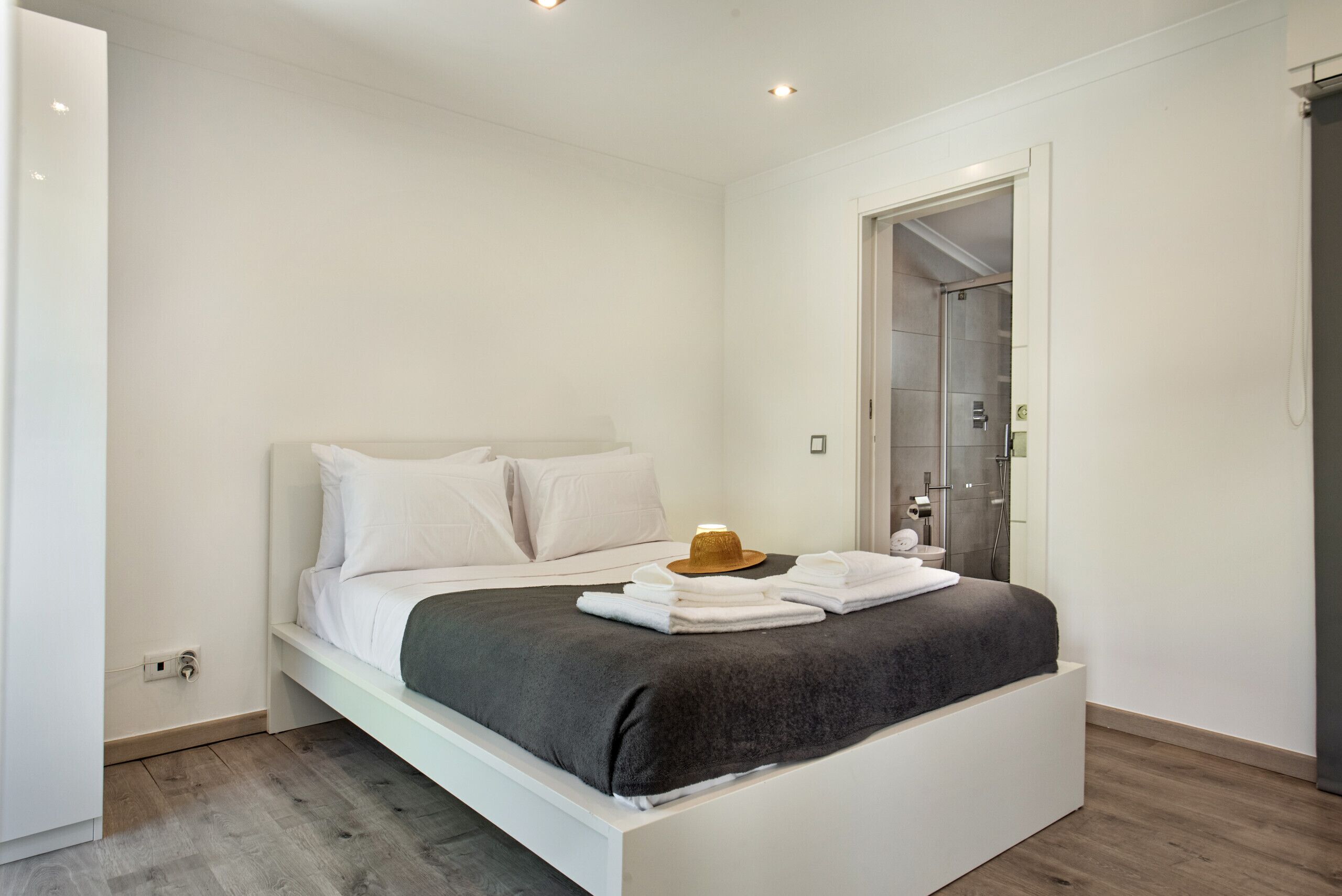 Een moderne slaapkamer met een bed, een kledingkast en een badkamer die door een open deur zichtbaar is.