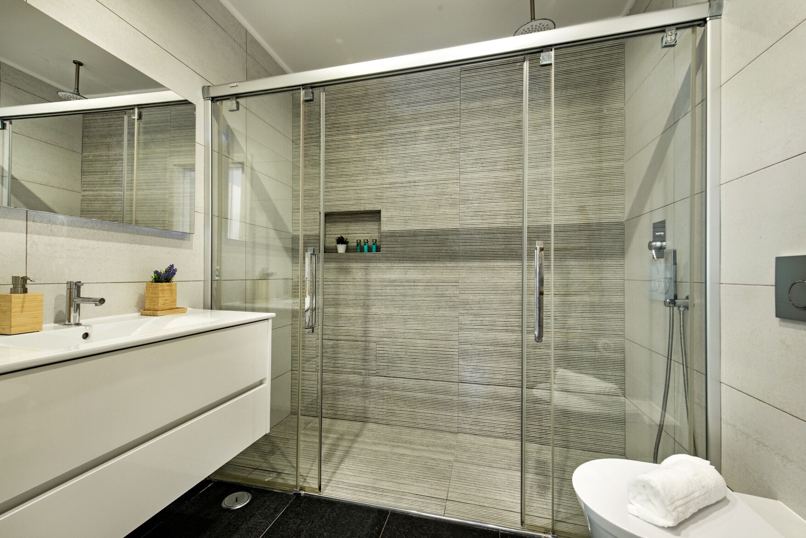 Une salle de bain moderne avec une douche à parois de verre, un lavabo blanc et des toilettes.
