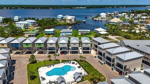 Un quartier résidentiel doté d’une piscine entourée de maisons, d’un port de plaisance et offrant une vue sur l’eau.