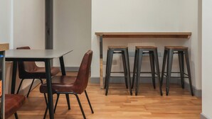 A small, modern dining area with a wooden table and four stools.