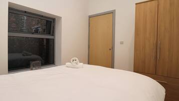 Un dormitorio con una cama grande, un armario de madera y una ventana con vista a un muro de ladrillo.