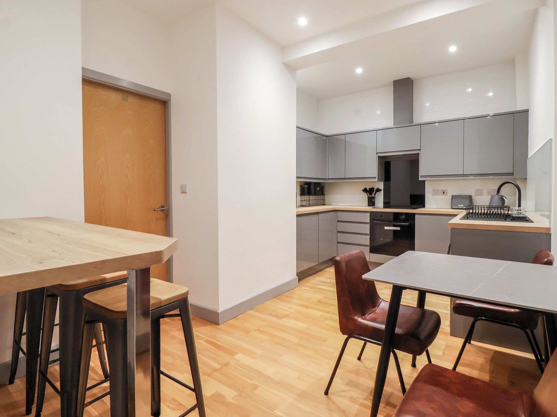 A modern kitchen with grey cabinets, a wooden countertop, and a stainless steel sink.