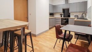 A modern kitchen with grey cabinets, a wooden countertop, and a stainless steel sink.