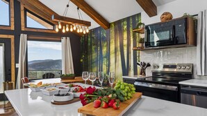 Une cuisine moderne dotée d’un grand îlot central, d’appareils électroménagers en acier inoxydable et offrant une vue magnifique.