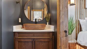 A bathroom with a wooden vanity, a round mirror, and a vessel sink.
