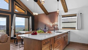 Une cuisine moderne dotée d’un grand îlot central, de meubles en bois et de luminaires suspendus.