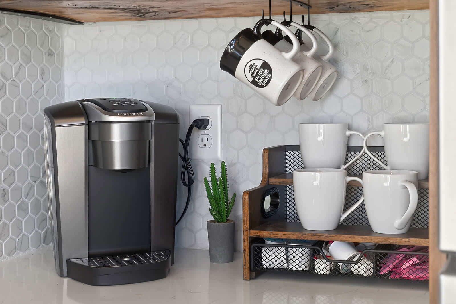 Eine Kaffeemaschine, ein Kaktus und ein Regal mit Tassen.