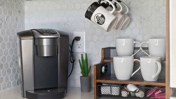 Eine Kaffeemaschine, ein Kaktus und ein Regal mit Tassen.