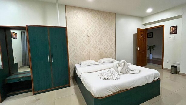 A hotel room with a bed, a wardrobe, and a mirror. - YSM Grand  (Guwahati)